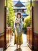 A woman in a yellow and blue kimono standing in front of a gate.