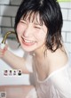 A woman in a white shirt is smiling and holding a faucet.