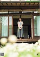 A woman standing in front of a wooden house.