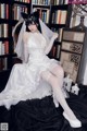 A woman in a wedding dress sitting on a chair.