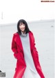 A woman in a red coat standing on a beach.