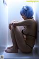 A woman with blue hair sitting on a window sill.