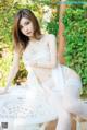 A woman in a white lingerie sitting on a white table.