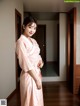 A woman in a pink kimono standing in a room.