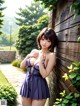 A woman in a blue dress leaning against a wooden fence.