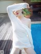 A woman in a white dress standing next to a swimming pool.