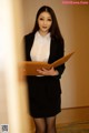 A woman in a business suit holding a folder.