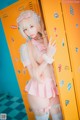 A woman in a pink and white outfit standing in front of a locker.