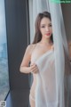 A woman in a white lingerie standing by a window.