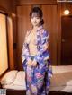 A woman in a blue kimono posing on a bed.