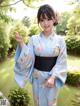 A woman in a blue kimono posing for a picture.