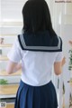 A woman in a white shirt and blue skirt standing in front of a staircase.