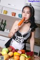 A woman in a maid outfit holding a carrot in her mouth.