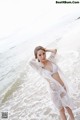 A woman in a white bikini standing on the beach.