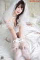 A woman in a wedding dress sitting on a bed.