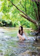 A woman sitting on a rock in a river.