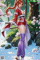 A woman in a red and white outfit holds a sword, standing amidst cherry blossoms near a waterfall.