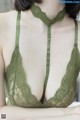 A woman wearing a green lace bra with a choker.