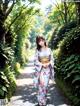 A woman in a kimono walking down a path in a park.